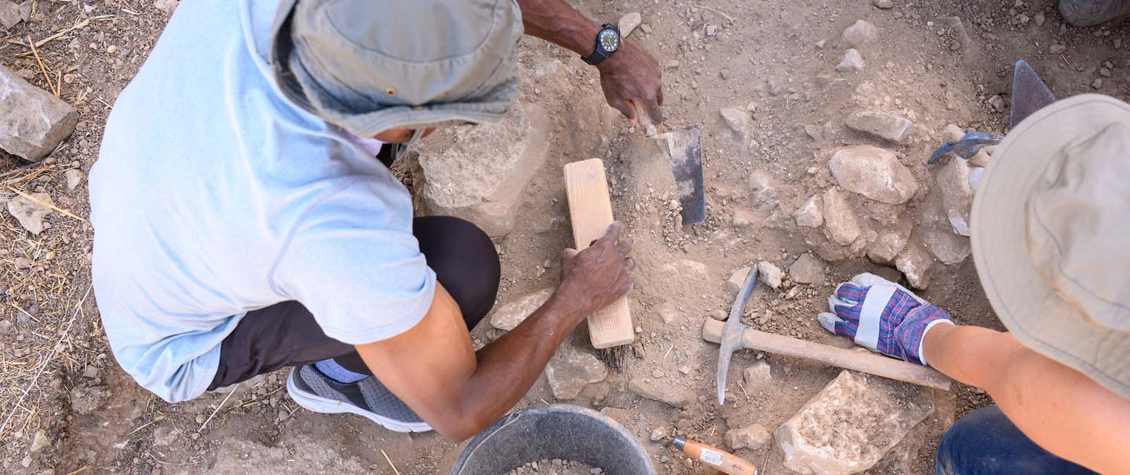 People dig in the dirt at an archealogical dig.
