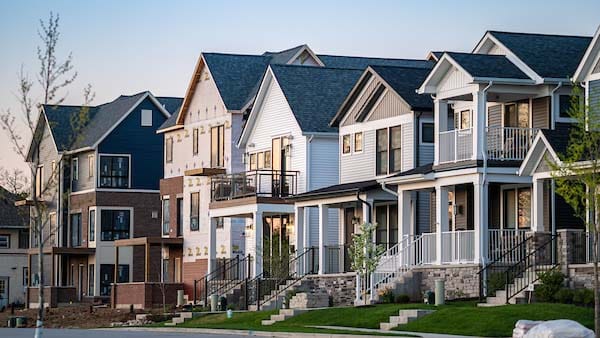 A row of modern, multi-story houses with different facades and a variety of textures and colors line a street.
