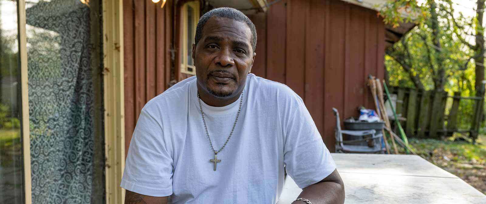 Keith Cooper sits on a picnic table outside his home.