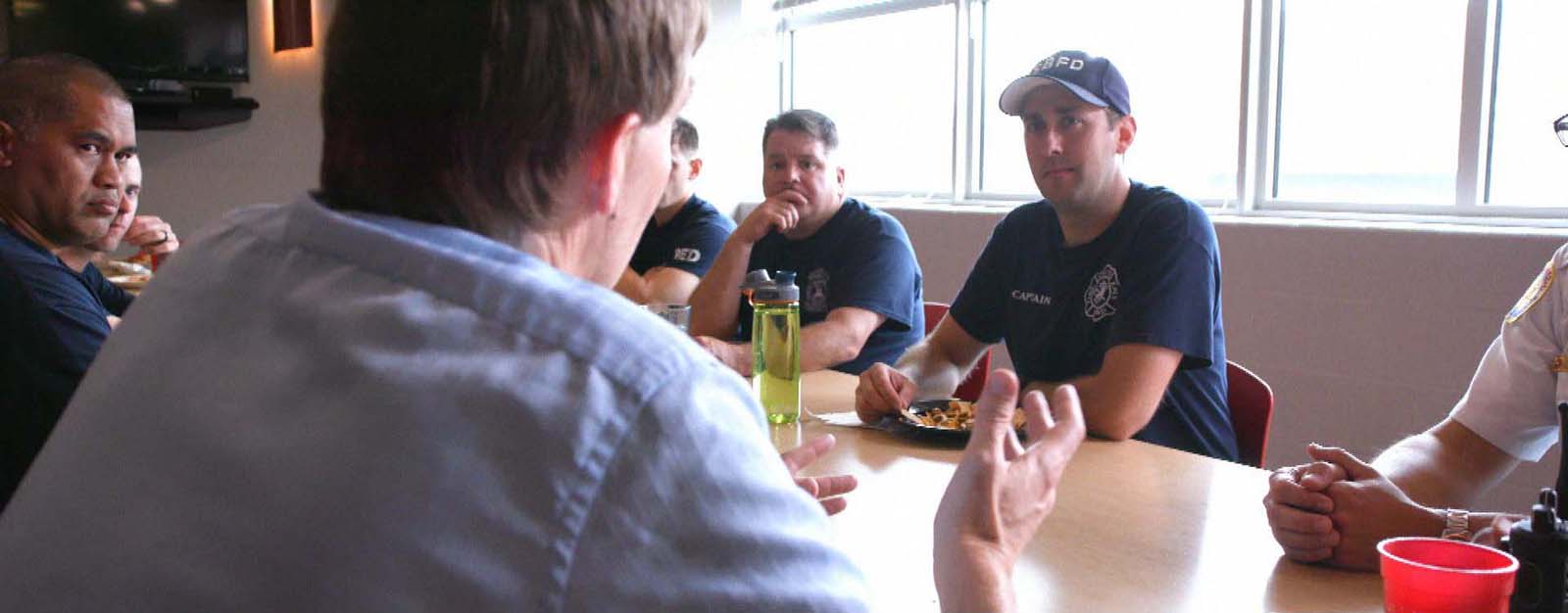 Peaslee sits and talks with a table of firefighters.