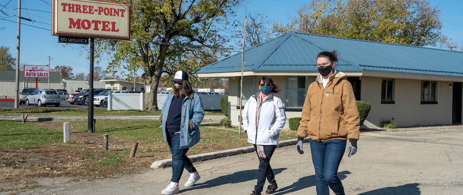 Three people walk outside the Three Point Motel