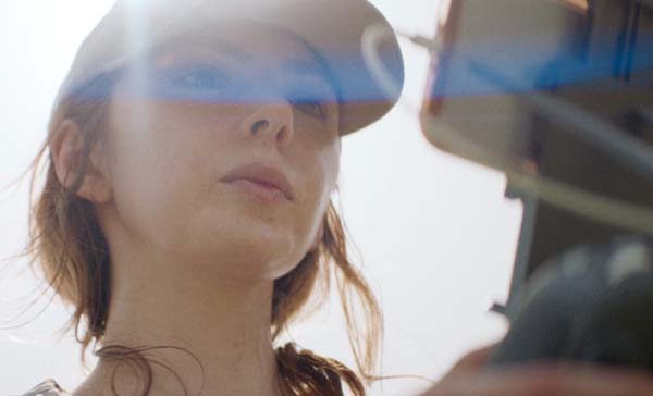 A woman wearing a hat looks at a screen on the controller of her drone.