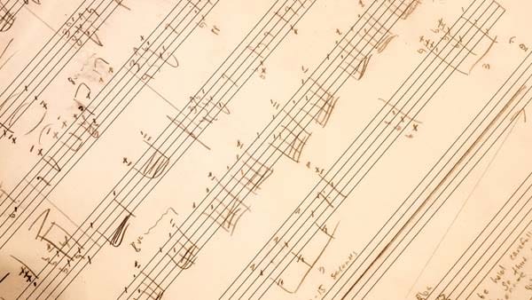 A close-up of a page of handwritten musical notation with notes, staves, and some text.