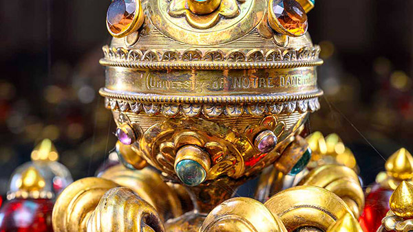 A close-up of a gold chalice with 'UNIVERSITY OF NOTRE DAME' engraved around the middle and a variety of colorful gems.