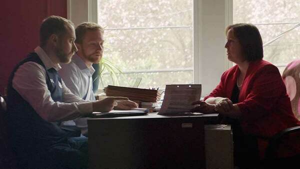 Three male law students interview with a woman at a table.