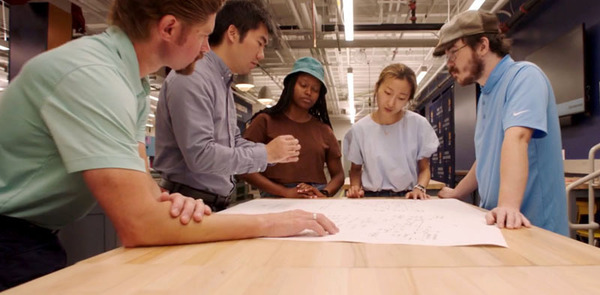 Two male professors research water sustainability with a group of students around a table.