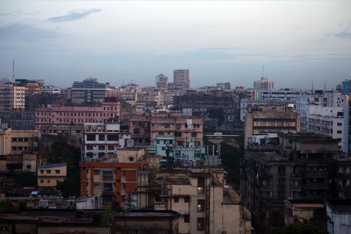 An overcast, wide shot of many colorful buildings packed together in a cityscape under a light gray sky.