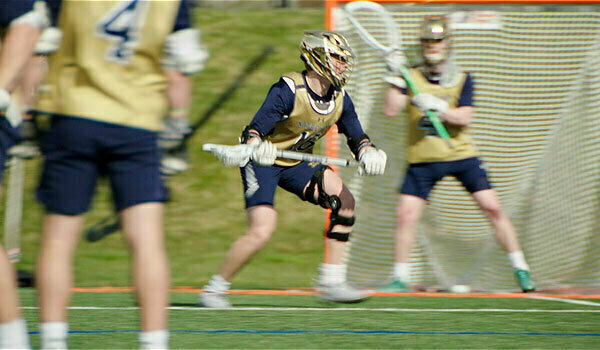 A male in glasses talks to a group of students at a desk.