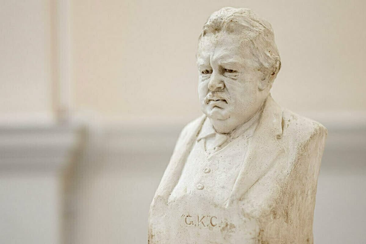 A stone bust of G.K. Chesterton looking slightly down and to the side. The letters 'G.K.C.' are carved into the front.