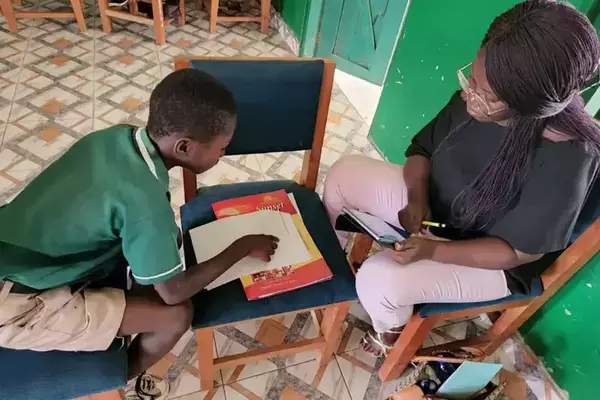 Recent graduate hugging child while smiling. Click to play.