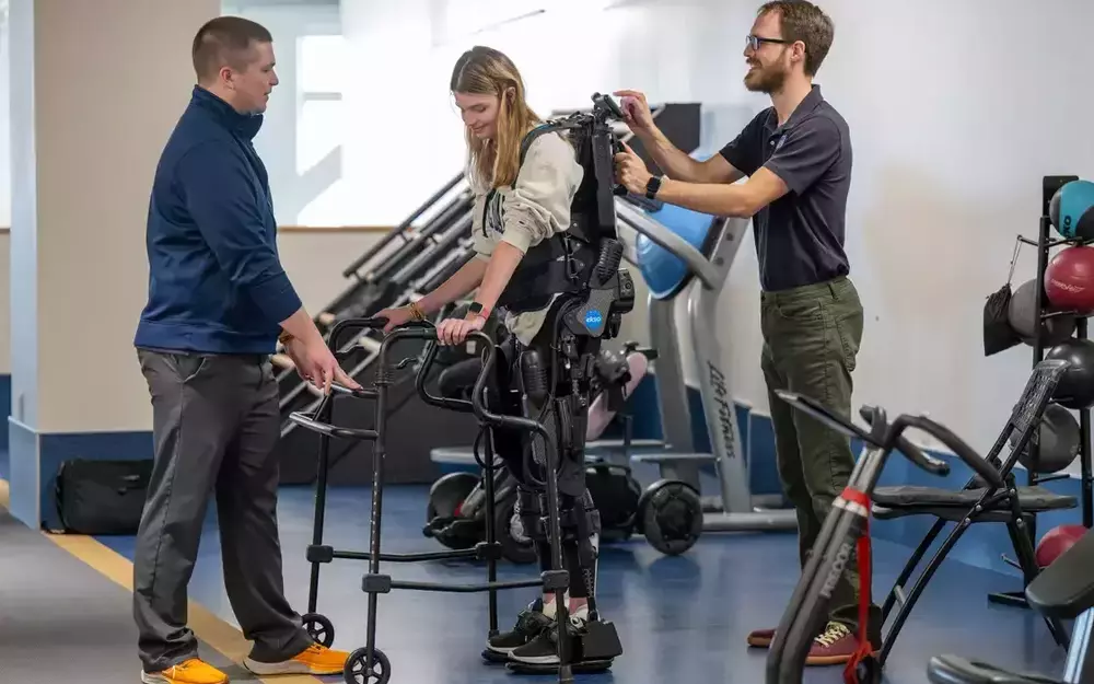 Annie Hamilton walks in physical therapy with the help of a full body suit.
