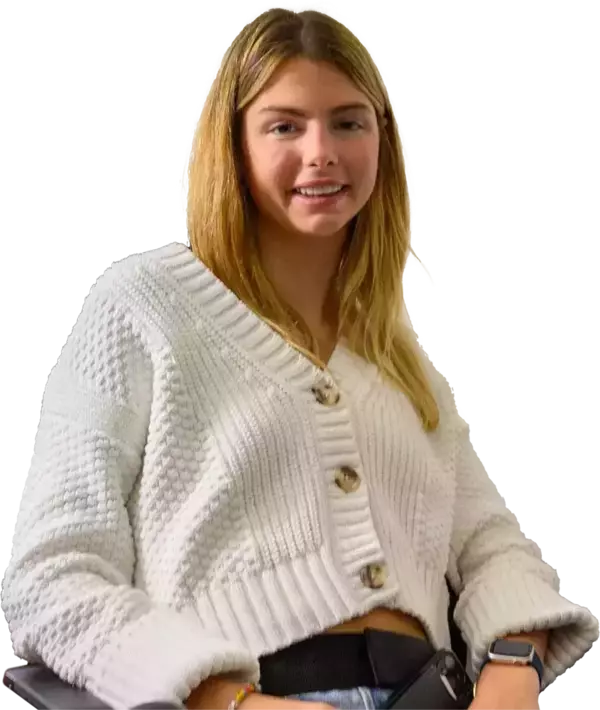 Annie Hamilton sitting in her wheelchair while wearing a white sweater.