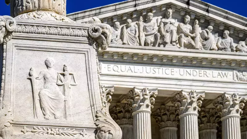 A detailed carving of Lady Justice holding scales and a sword is seen in the foreground with the United States Supreme Court building in the background. The words "Equal Justice Under Law" are engraved above the building's entrance. The image evokes themes of law, justice, and the American legal system.