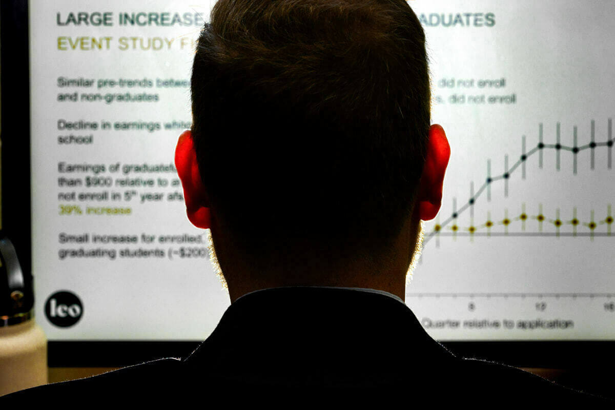 A person views a projected chart showing a large increase in earnings for graduates.