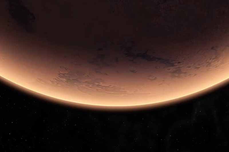 A close-up view of the rust-colored surface of Mars as it curves into the blackness of space. 