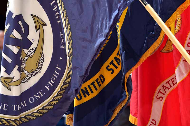 The United States Navy and Marine Corps flags hang alongside other flags, shown in a close-up view. 