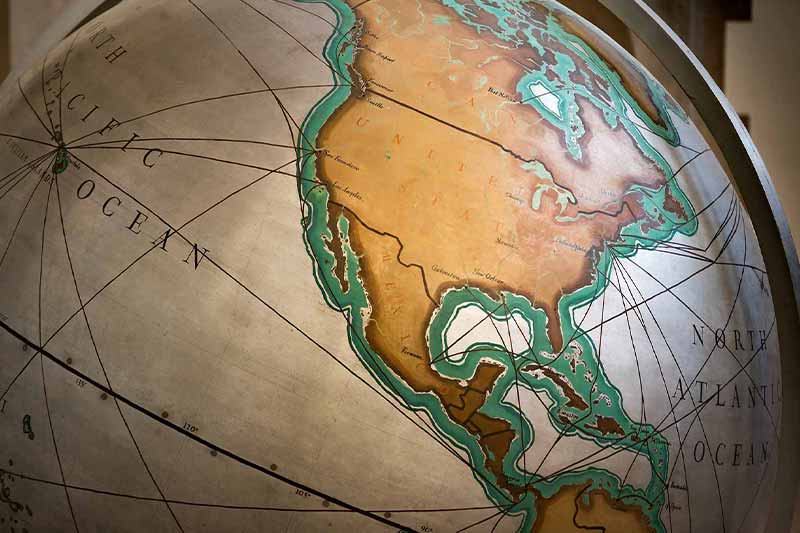 A large, vintage-style globe is shown, with a close-up of the continents of North and South America. 
