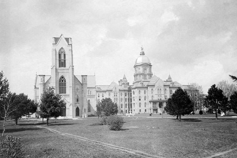 A black-and-white photograph of the University of Notre Dame campus from the late 19th or early 20th century.