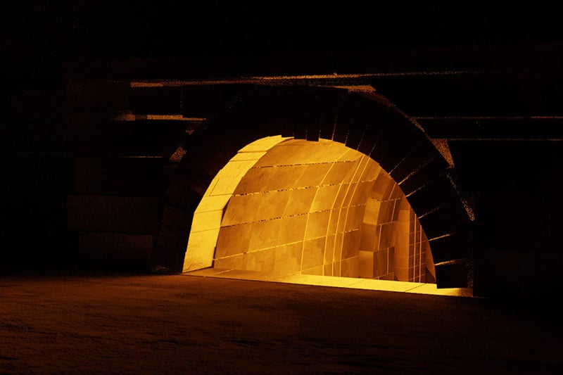 A glowing archway in a dark, brick-like space.
