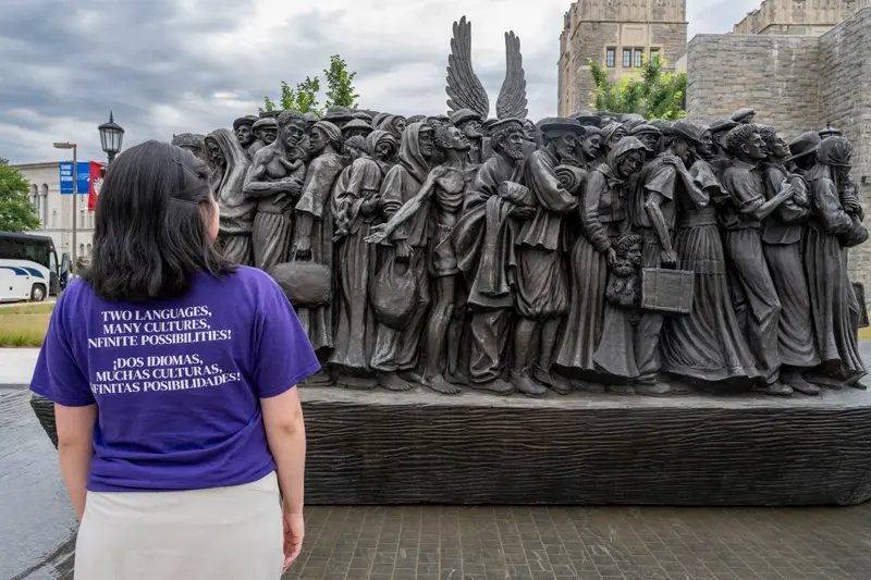 A female with dark hair gazes at the Angels Unawares sculpture, a bronze sculpture of migrants and refugees from various lands crowded on a 20-foot boat at the Catholic University of America in Washington, D.C.