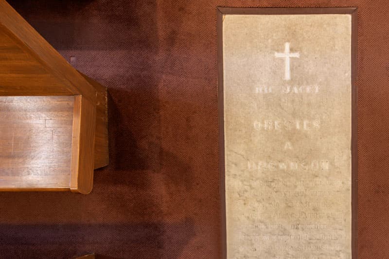 Edge of a wooden pew and the floor marker for Orestes A. Brownson in the Basilica of the Sacred Heart at the University of Notre Dame.