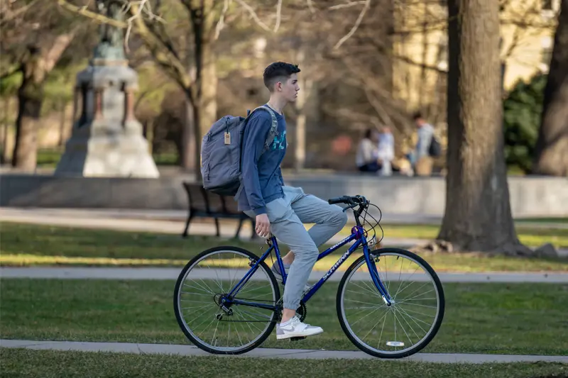 A male student riding his bike across campus