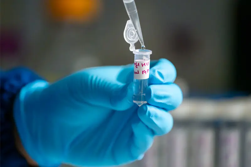 A gloved hand holding a sample of fentanyl in a test tube.