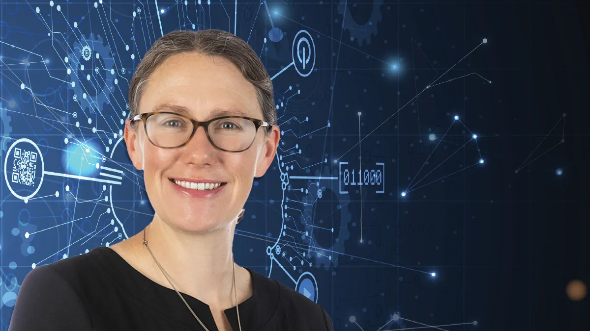 A smiling woman with glasses and brown hair pulled back stands in front of a dark blue background with abstract white digital lines and binary code.
