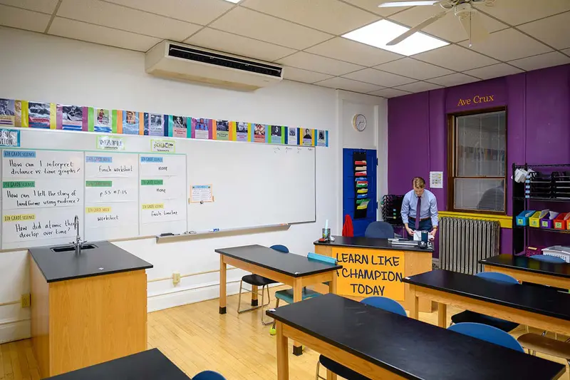 Notre Dame student Andy Miles stands at the front of his classroom wearing a shirt and tie.