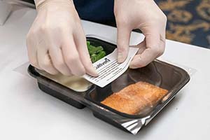 Hands put a label on a package of food.