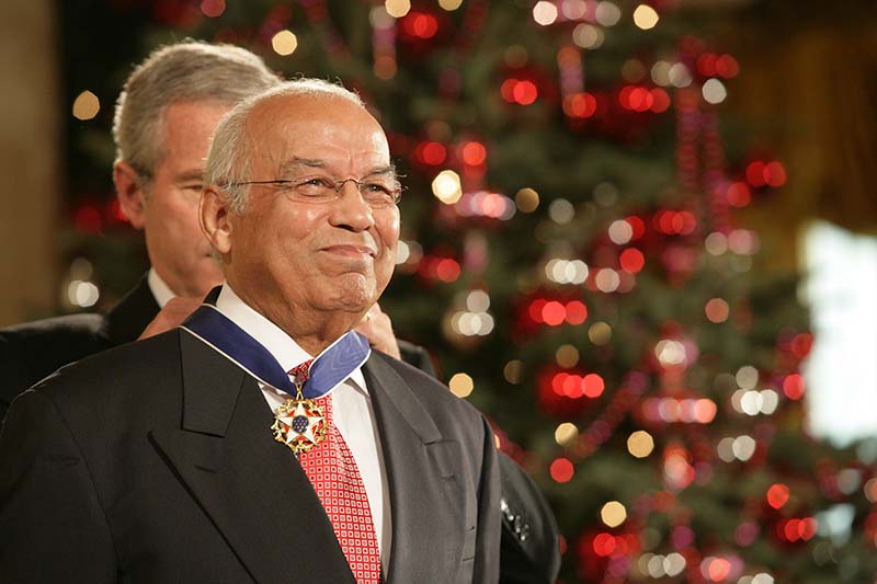 President George W. Bush puts the Medal of Freedom around Francis' neck in front of a Christmas tree.