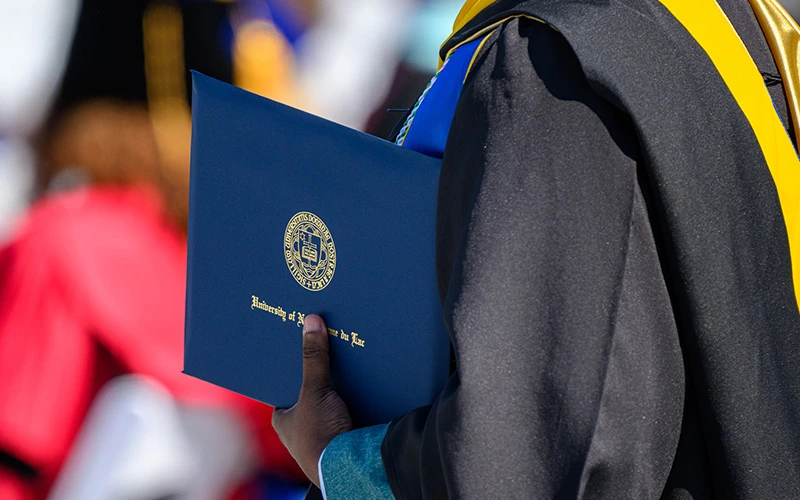 A graduating student holds a University of Notre Dame diploma.