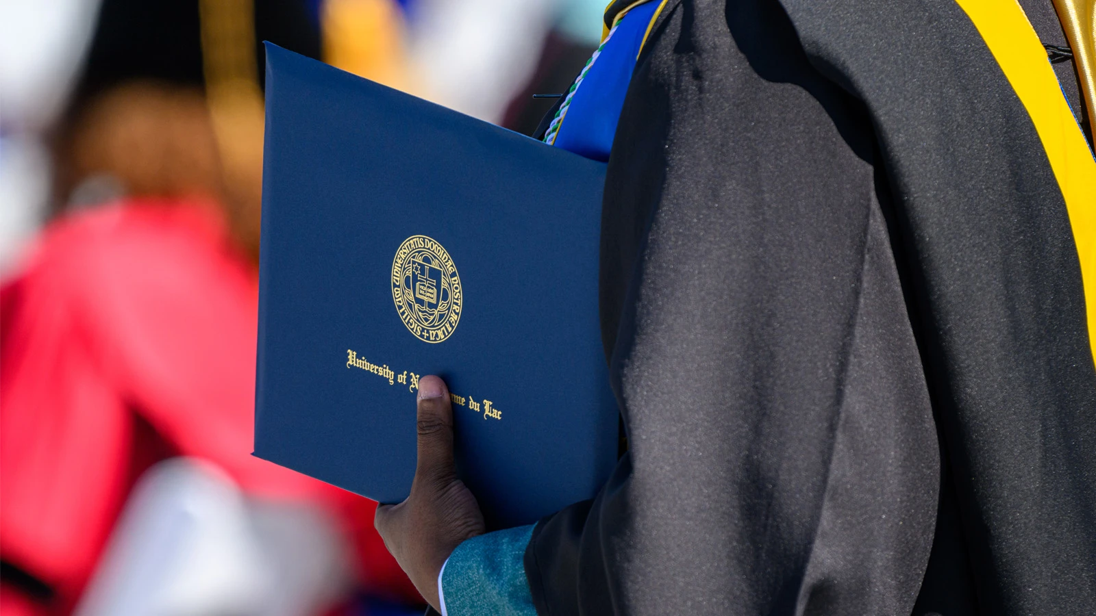 A graduating student holds a University of Notre Dame diploma.