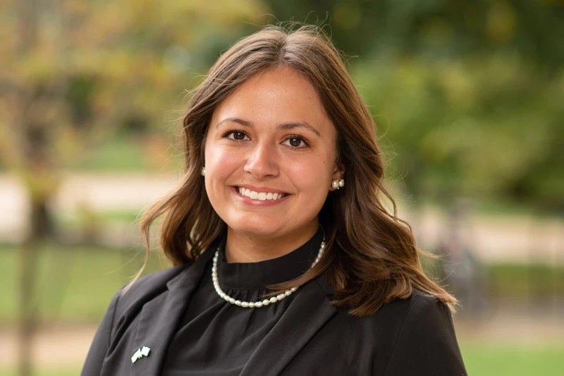 A young, brown-haired woman in a black top.