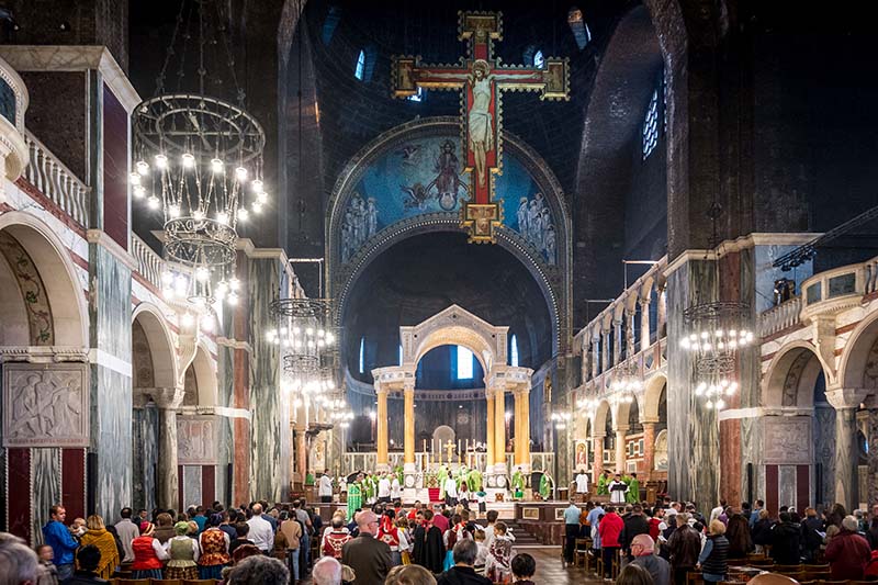 The Cathedral is filled with people gathered for Mass. A crucifix hangs above the alter.
