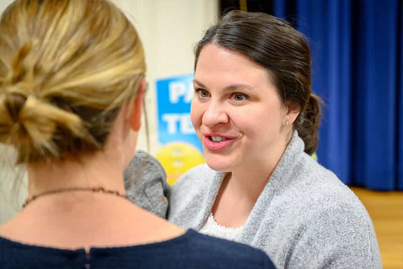 A closeup of a woman's face speaking to another woman.