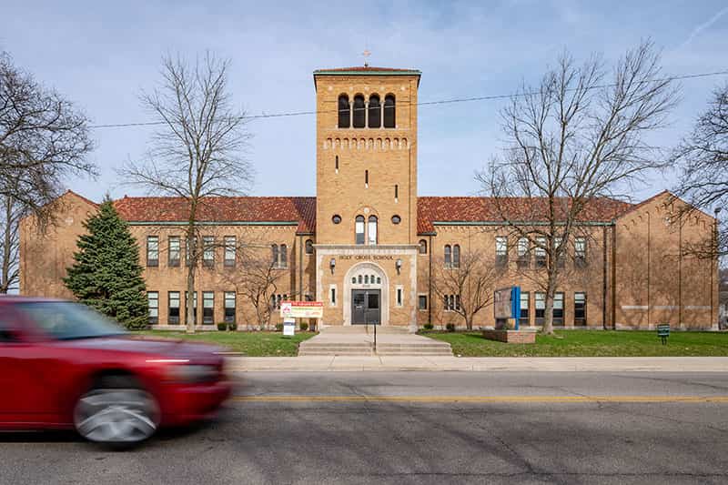 A school building along side bare trees and a blue sky.