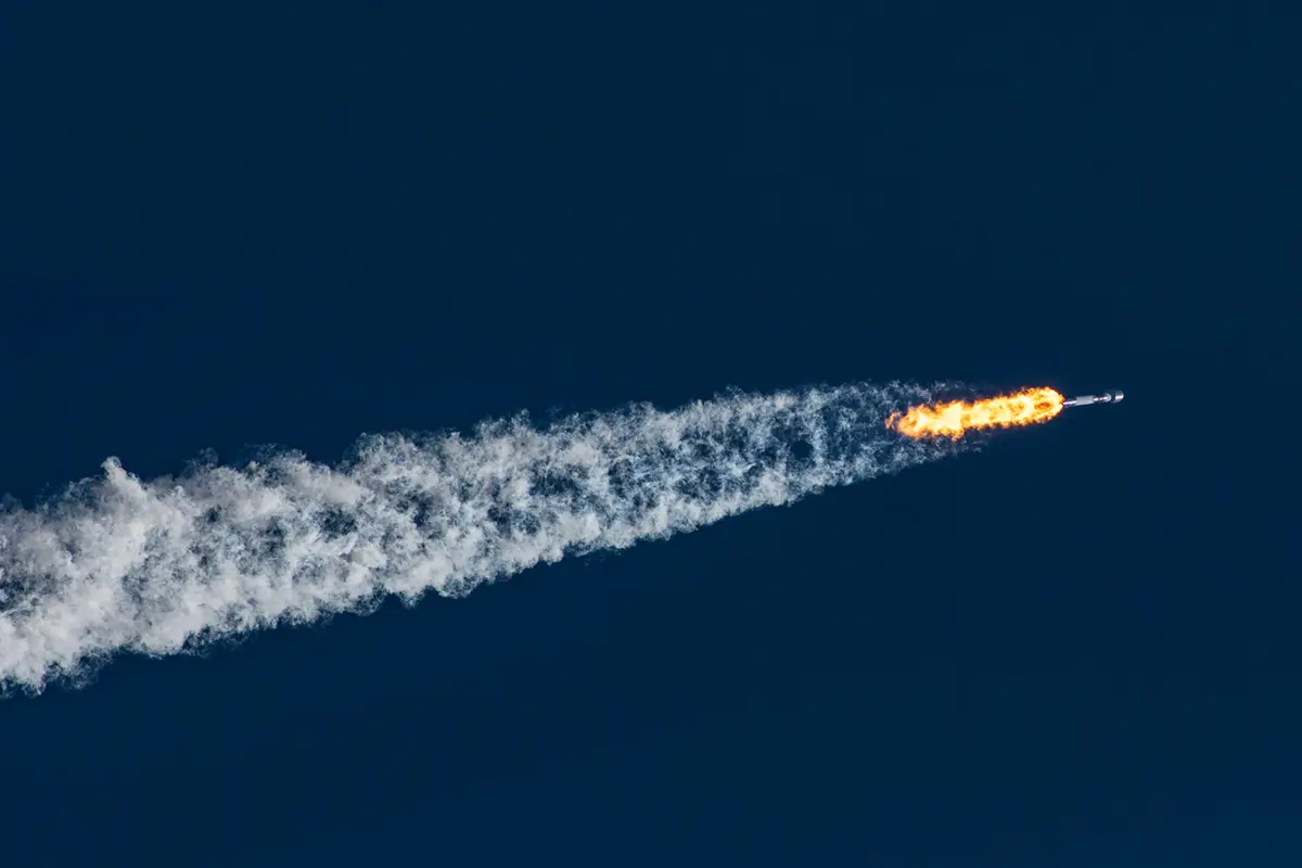 A rocket takes off from a launch pad, surrounded by billowing smoke and flames.