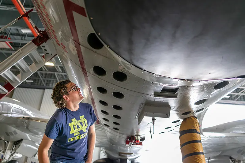 David Richter inspecting the belly of an aircraft before takeoff in a hangar in Florida.