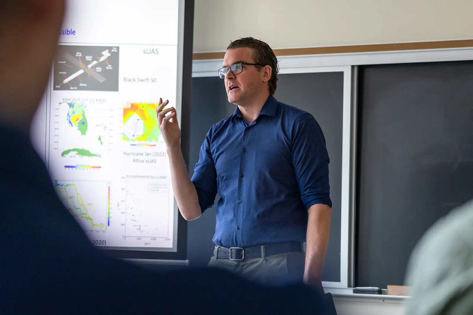 David Richter standing in front of a blackboard and projector screen teaching a class at the University of Notre Dame.