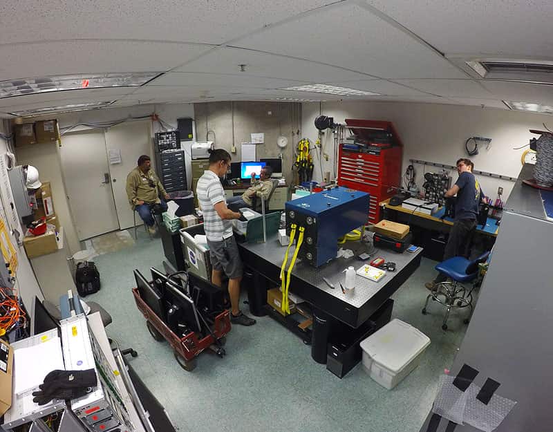 Three people aer in a room wokring on the iLocater that sits on top of a large table.