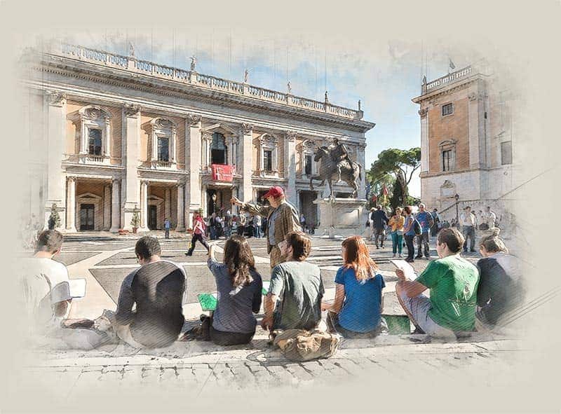 Students sit on cobblestone stairs, sketching and as they listen to their teacher who is standing in front pointing to buildings in the distance.