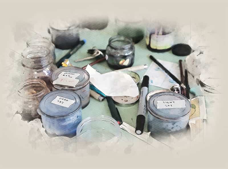 Labled paint jars and other art tools lay on a table.