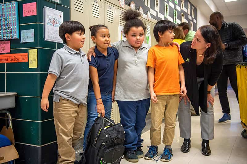 Children pose in their school's hallway with Paqui Kelly.