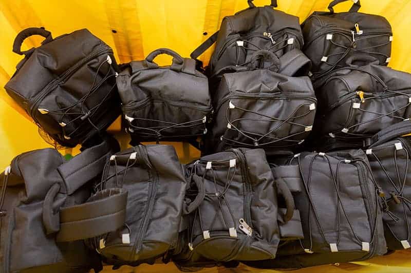 Several backpacks piled in a bin.