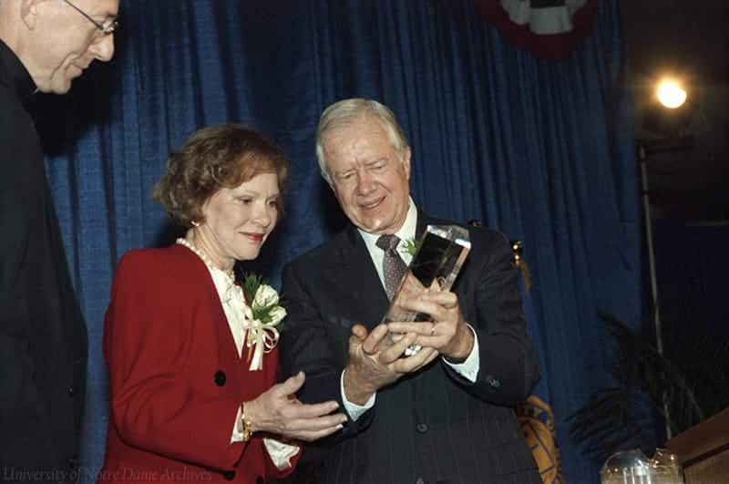 Jimmy and Rosalynn Carter accept the Notre Dame Award, smiling at it in their hands.