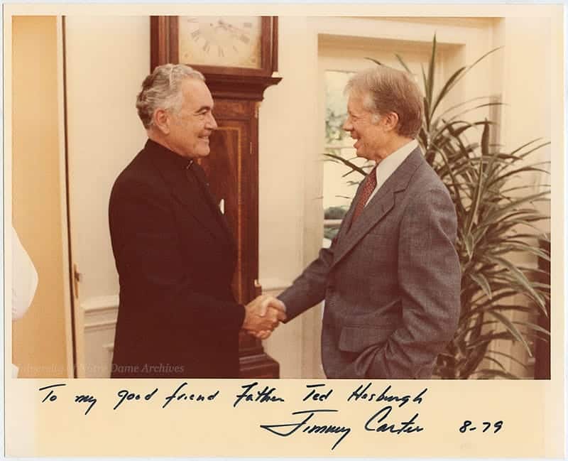 Jimmy Carter shakes Father Hesburgh's hand in the Oval Office. It is signed To my good friend Father Ted Hesburgh Jimmy Carter 8-79