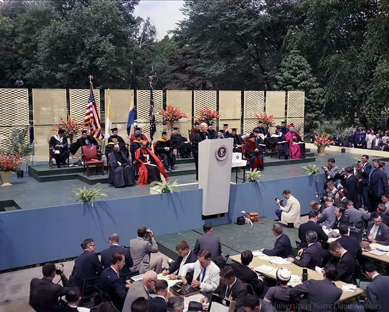 A color photograph of an outdoors commencement stage with Eisenhower speaking at the podium.