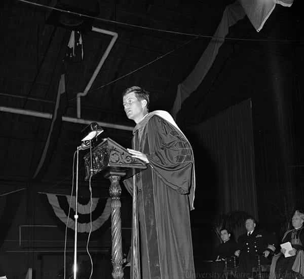 Kennedy wears honorary degree garb and speaks at a podium.