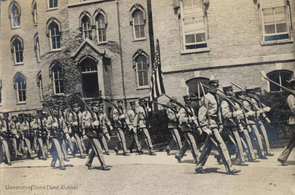 A Notre Dame military company marching on campus in front of Main Building, c1910s.